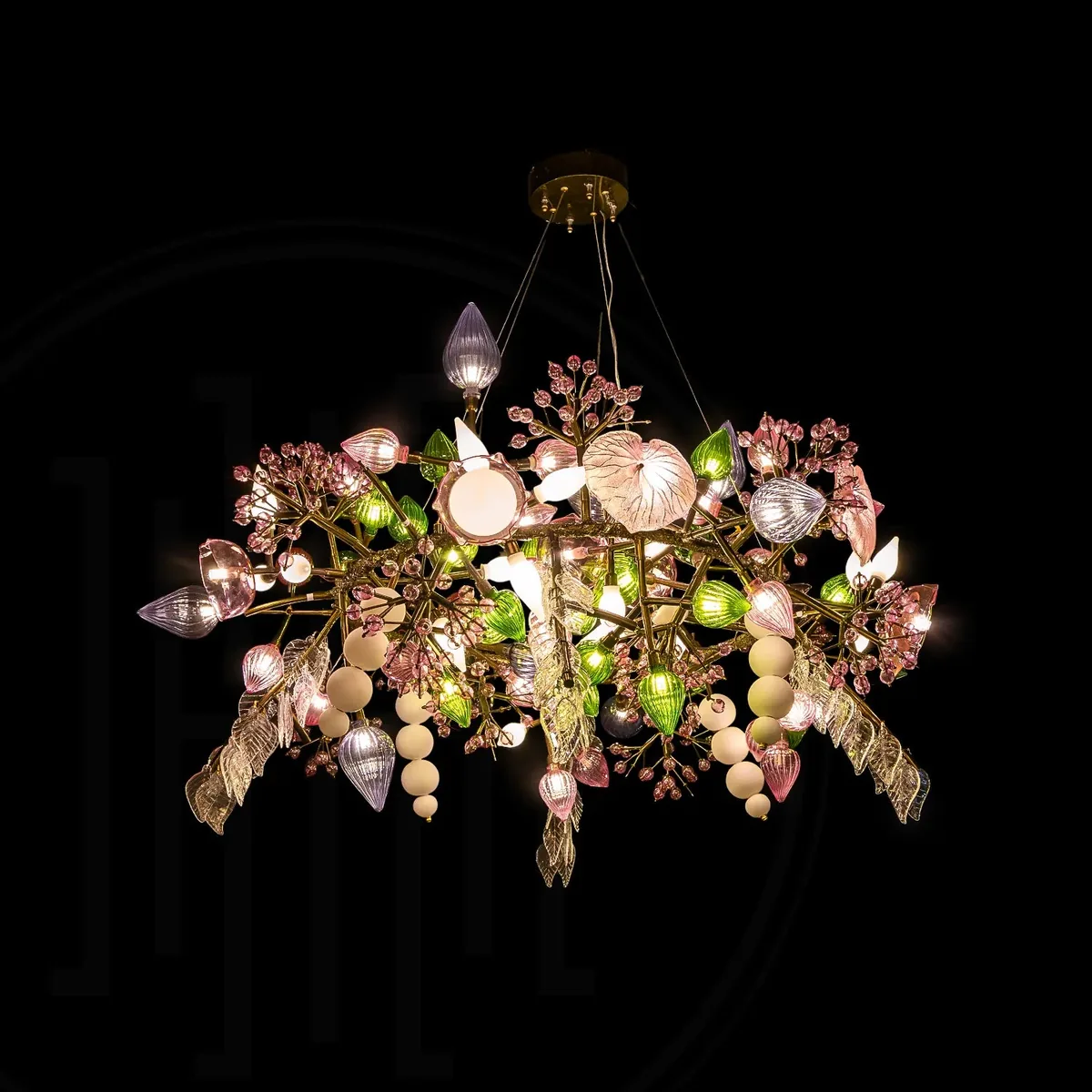 Harold Electricals Pandora Chandelier lit against a black background, showing brass branches carrying pink, green and opal glass fruit and leaf pendants