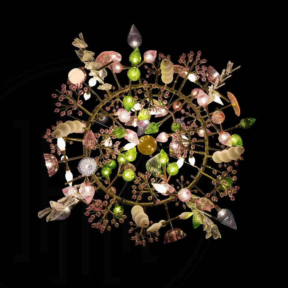 The Pandora Chandelier viewed from below, showing brass branches radiating outward in a circular plan carrying pink, green and white glass elements